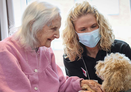 Female Encore resident petting a therapy dog